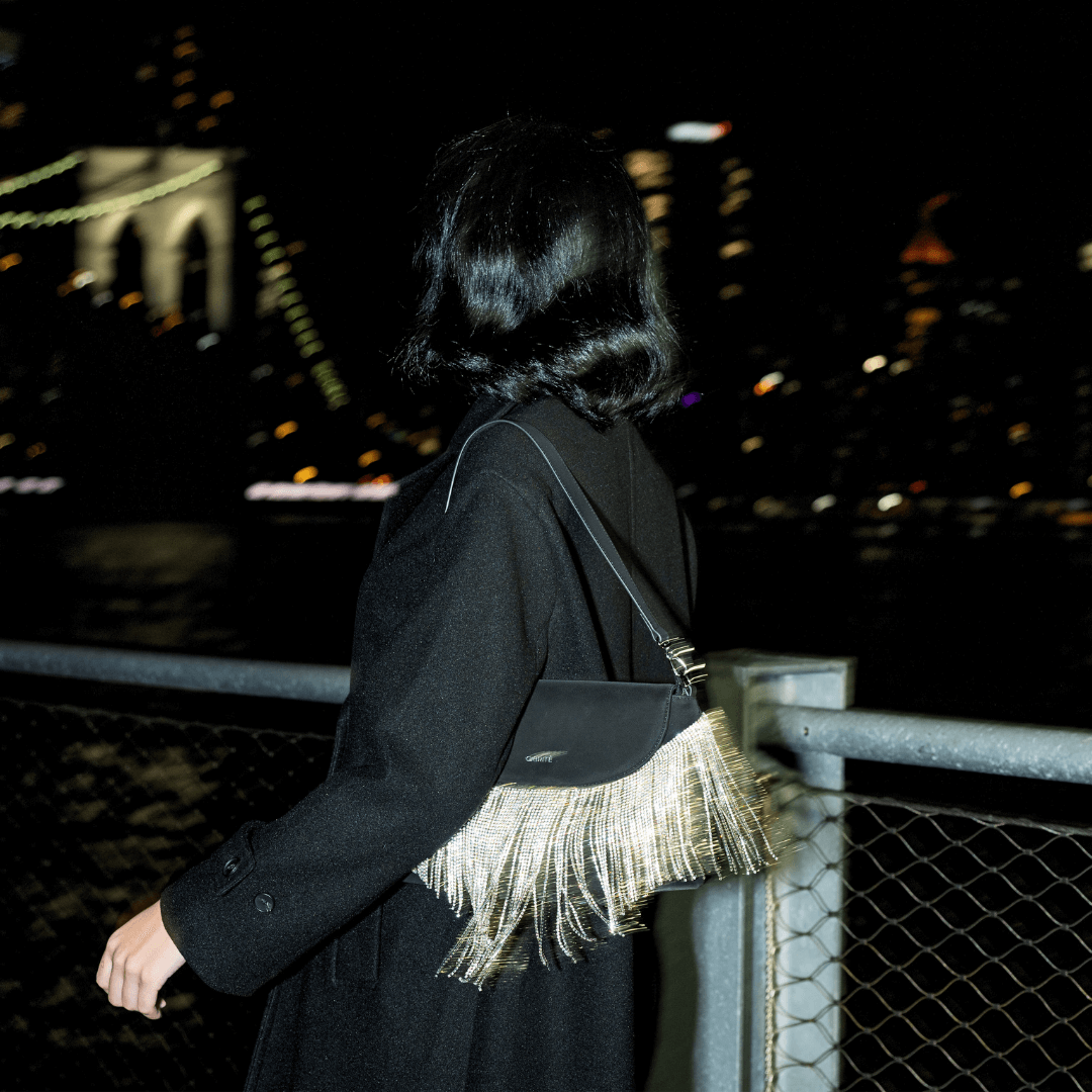 A black vegan suede shoulder bag with layers of soft, swaying fringe, designed to evoke a modern Western style.