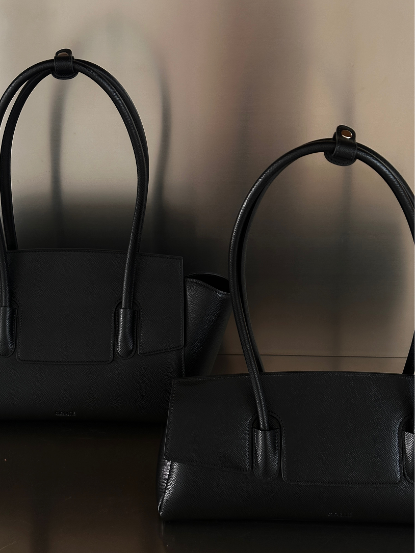 Two black vegan leather tote bags or shoulder bags from Giarité, likely the Valyn East West model, are displayed against a muted background.